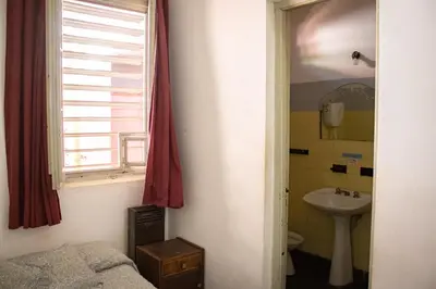 a bathroom with a bed and a sink and a window at El Viaje Hostel in Mina Clavero