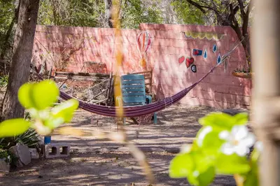 a hammock and chairs in front of a wall at El Viaje Hostel in Mina Clavero