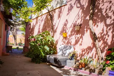 a pink wall with a bench next to a building at El Viaje Hostel in Mina Clavero