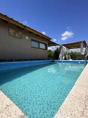 a swimming pool with blue water in front of a house at Los Frutales in Villa Carlos Paz