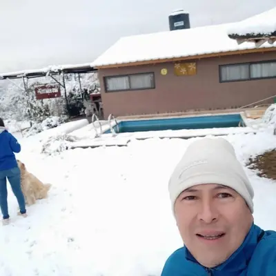 a man standing in the snow in front of a house at Los Frutales in Villa Carlos Paz