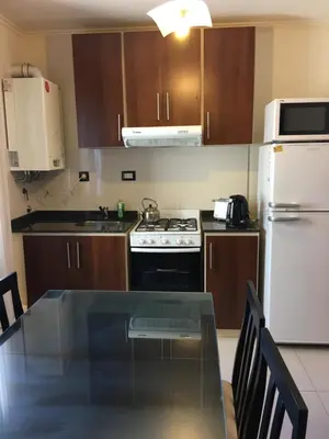 a kitchen with a table and a white refrigerator at Aires de la Villa in Villa Carlos Paz
