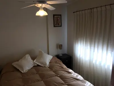 a bedroom with a bed with pillows and a ceiling fan at Aires de la Villa in Villa Carlos Paz