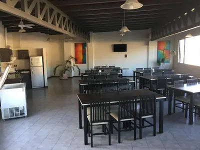 a dining room with tables and chairs and a kitchen at Aires de la Villa in Villa Carlos Paz