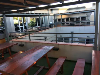 a row of wooden benches in a room with tables at Aires de la Villa in Villa Carlos Paz