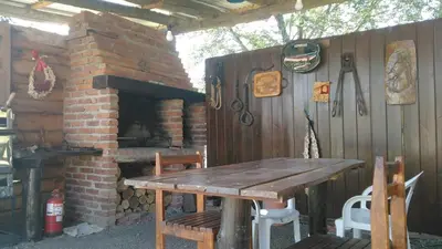 a wooden table and a brick fireplace in a patio at Balcon Al Paradiso in Santa Rosa de Calamuchita