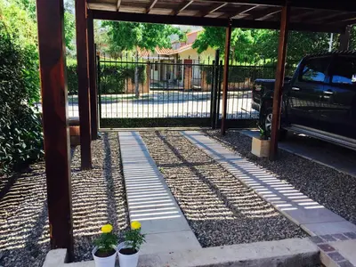 a covered walkway with two potted plants and a fence at La Carolina in Santa Rosa de Calamuchita