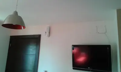 a flat screen tv sitting on a wall with a lamp at Aires de la Villa II in Villa Carlos Paz