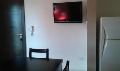 a kitchen with a table and a television on the wall at Aires de la Villa II in Villa Carlos Paz