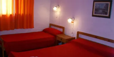 a small room with two beds and a window at Hosteria Columbia in Mina Clavero