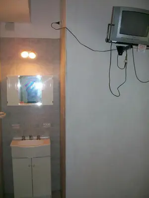 a bathroom with a sink and a tv on the wall at Hosteria Columbia in Mina Clavero