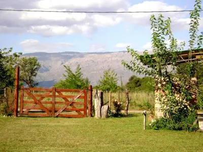 a wooden gate in a field with mountains in the background at Pasos Cortos Cabañas Nono in Nono