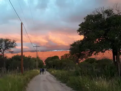 two people walking down a dirt road at sunset at Pasos Cortos Cabañas Nono in Nono