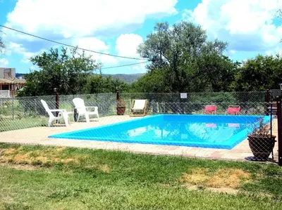 a swimming pool with two lawn chairs and a fence at Pasos Cortos Cabañas Nono in Nono
