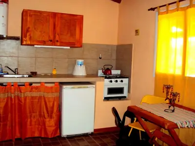 a kitchen with a white refrigerator and a table and a stove at Pasos Cortos Cabañas Nono in Nono