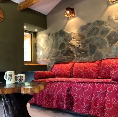 a red couch in a living room with a stone wall at Posada del Halcón - Cabañas y Suites in Villa General Belgrano