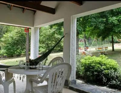 a porch with a white table and chairs and a swing at Posada del Halcón - Cabañas y Suites in Villa General Belgrano