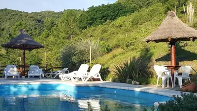 a group of chairs and umbrellas next to a swimming pool at Posada del Halcón - Cabañas y Suites in Villa General Belgrano