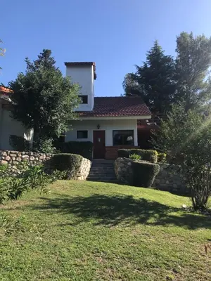 a house with a stone fence and a yard at Posada del Halcón - Cabañas y Suites in Villa General Belgrano