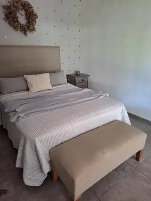 a bedroom with a large bed with a bench next to it at Posada Del Angel in Villa Serranita