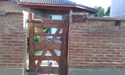 a wooden gate in a brick wall with a dog behind it at La Casita de Sil in Mina Clavero