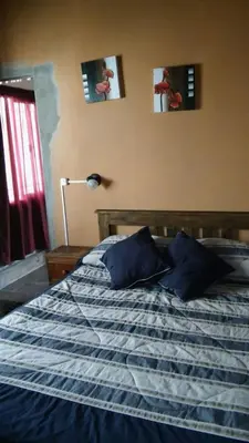 a bed in a bedroom with two pictures on the wall at La Casita de Sil in Mina Clavero