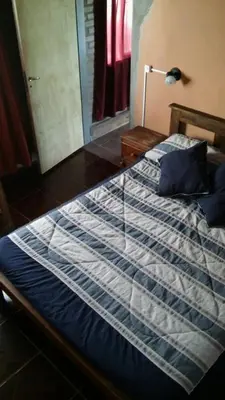 a bed with a blue and white blanket and a lamp at La Casita de Sil in Mina Clavero