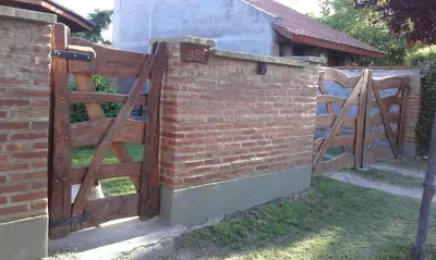 a brick fence with a wooden gate in a yard at La Casita de Sil in Mina Clavero