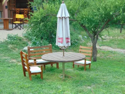 a wooden table with an umbrella and two chairs at Hosteria Aguas Claras in Mina Clavero