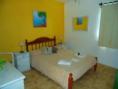 a bedroom with a bed in a room with yellow walls at Hosteria Aguas Claras in Mina Clavero