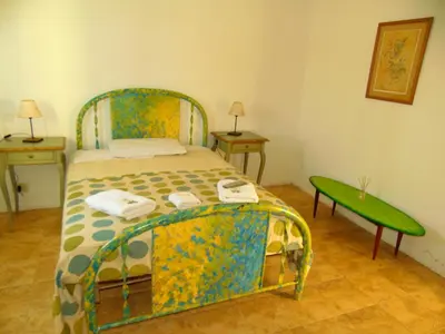 a bedroom with a bed and two tables and a green bench at Hosteria Aguas Claras in Mina Clavero