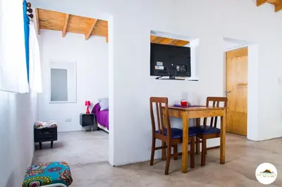 a room with a table and chairs and a bedroom at Entre Sierras y Pajaros in Las Rabonas