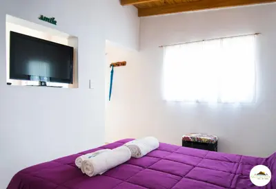 a bedroom with a purple bed with a flat screen tv at Entre Sierras y Pajaros in Las Rabonas
