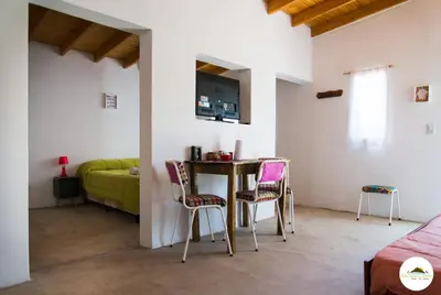 a room with a table and chairs and a bed at Entre Sierras y Pajaros in Las Rabonas