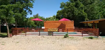 a wooden fence with a sign and umbrellas at Cabañas Villa Bonita in Villa Ciudad Parque