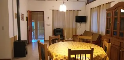 a dining room with a table and a living room at Cabañas Villa Bonita in Villa Ciudad Parque