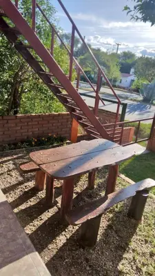 a wooden bench sitting on the ground with a staircase at Lo de Lili Departamentos Mina Clavero in Mina Clavero