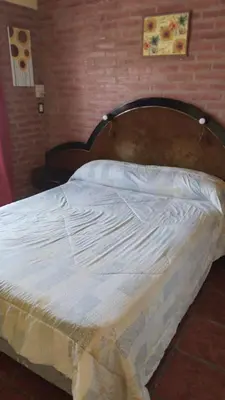 a bed with a wooden headboard in a bedroom at Lo de Lili Departamentos Mina Clavero in Mina Clavero