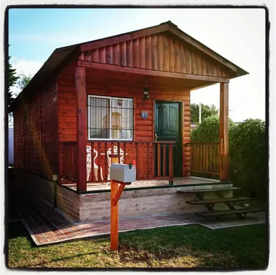 a small wooden cabin with a green door and a mailbox at Cabañas 57 in Villa Carlos Paz