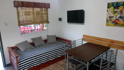 a room with two beds and a table and a tv at Cabañas 57 in Villa Carlos Paz