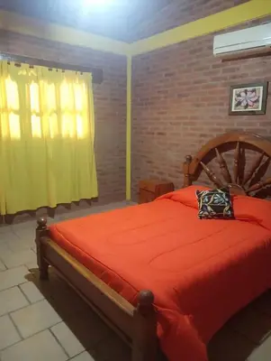 a bedroom with a bed with an orange comforter at Cabañas mi Sueño in Villa Carlos Paz