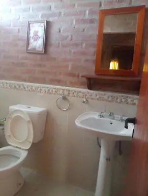 a bathroom with a toilet and a sink and a mirror at Cabañas mi Sueño in Villa Carlos Paz