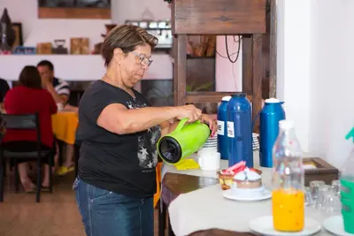 a woman is standing at a counter with a green mixer at Hotel Los Aromos in Mina Clavero