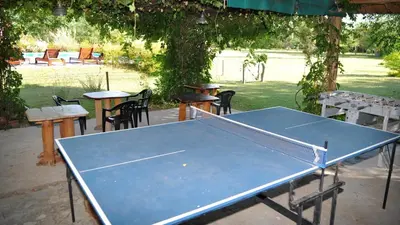 a ping pong table in a park with tables and chairs at El Caserio Casas de Campo in Villa Cura Brochero