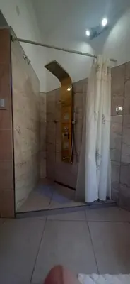 a bathroom with a shower with white curtains at Apart y Suite Portal del Luz in Mina Clavero