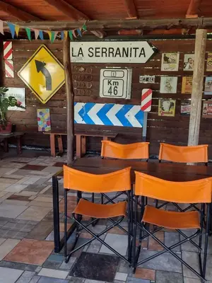 a table and chairs in a room with a sign at Cabañas Buen Dia in Villa Serranita