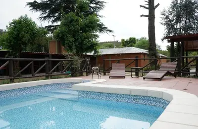 a swimming pool with two chairs and a table at Cabañas Buen Dia in Villa Serranita