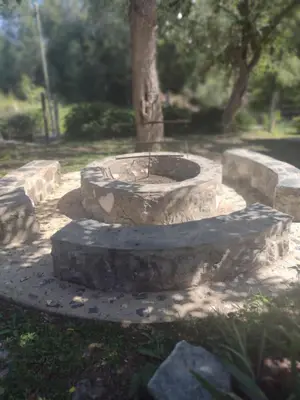 a stone fountain in a park with a tree at Cabañas Buen Dia in Villa Serranita
