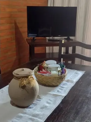 a table with a vase and a basket on a table with a television at Cabañas Buen Dia in Villa Serranita