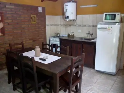 a kitchen with a wooden table and a refrigerator at Cabañas Buen Dia in Villa Serranita